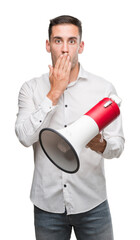 Handsome young man holding microphone cover mouth with hand shocked with shame for mistake, expression of fear, scared in silence, secret concept