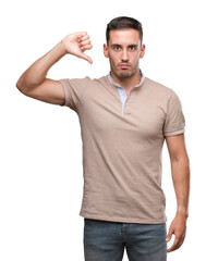 Handsome young man with angry face, negative sign showing dislike with thumbs down, rejection...