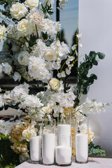 Decor details closeup. Location for luxury wedding ceremony. Arch decorated white flowers, greens, greenery, candles. Trendy decor in backyard. Celebration baptism concept. Birthday party reception.