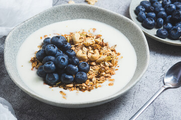 Granola with yogurt and blueberries in a plate on a gray background