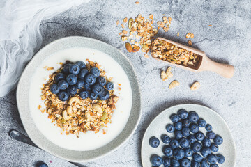 Granola with yogurt and blueberries in a plate on a gray background