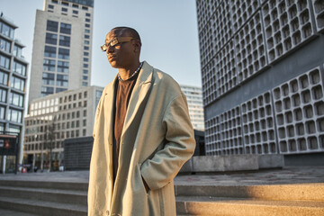 Handsome multiracial man with short hairstyle standing at the sunny street