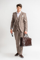 A man in a business three-piece suit with a large travel bag for business trips.