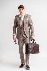 A man in a business three-piece suit with a large travel bag for business trips.
