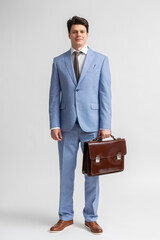 Young man in a blue business suit, white shirt and tie with a leather briefcase