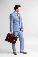 Young man in a blue business suit, white shirt and tie with a leather briefcase