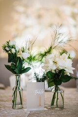 Table number 1. Stands, sign number one. Setup detail. Luxury reception. Elegant table decorated composition flowers in party area. Beautifully organized event. Wedding hall with atmospheric decor