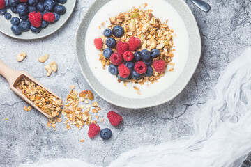 Granola with yogurt, raspberries, blueberries in a plate on a gray background
