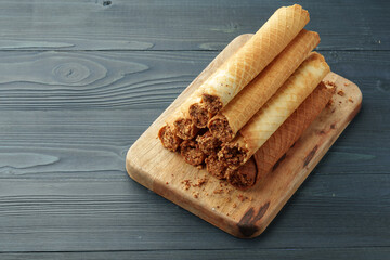 Waffle tubes with chocolate filling on wooden board