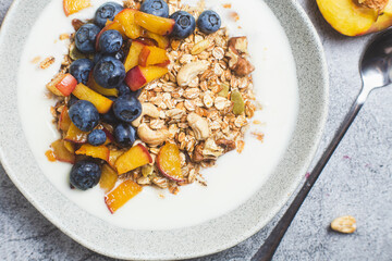 Granola with yogurt, peach, blueberries in a plate 