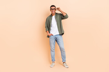 Fototapeta premium Full length photo of positive nice young man arm touch eyeglasses posing isolated on beige color background