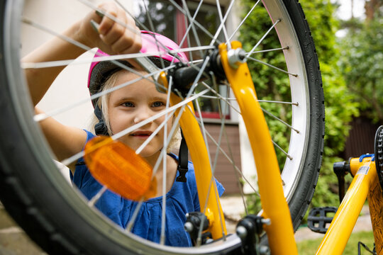 little girl repairing bicycle wheel with wrench at home backyard