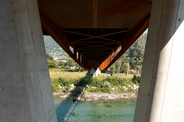 Detail of the pylons of a rusty modern bridge, under which the river Ticino flows. Sunny summer day