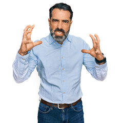Middle aged man with beard wearing business shirt shouting frustrated with rage, hands trying to strangle, yelling mad