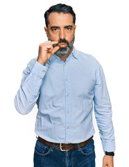 Middle aged man with beard wearing business shirt mouth and lips shut as zip with fingers. secret...