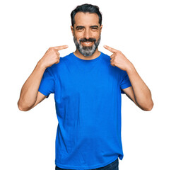Middle aged man with beard wearing casual blue t shirt smiling cheerful showing and pointing with fingers teeth and mouth. dental health concept.