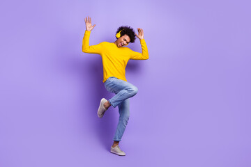 Fototapeta na wymiar Full size portrait of positive satisfied man listen music headphones dancing empty space isolated on purple color background