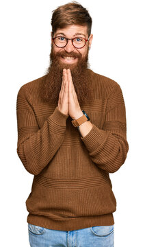 Young irish redhead man wearing casual clothes and glasses praying with hands together asking for forgiveness smiling confident.