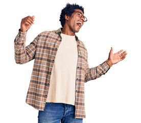 Handsome african american man with afro hair wearing casual clothes and glasses dancing happy and cheerful, smiling moving casual and confident listening to music