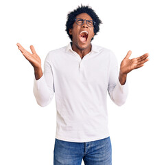 Handsome african american man with afro hair wearing casual clothes and glasses celebrating mad and...