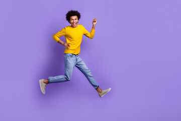 Full length body photo of jumping crazy overjoyed optimistic funky wear denim jeans yellow shirt isolated on purple color background