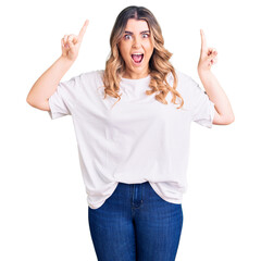 Young caucasian woman wearing casual clothes smiling amazed and surprised and pointing up with fingers and raised arms.