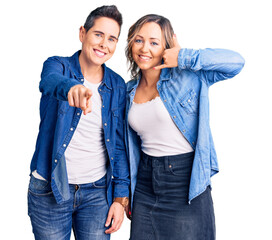 Couple of women wearing casual clothes smiling doing talking on the telephone gesture and pointing to you. call me.