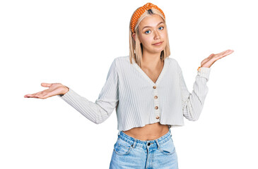 Beautiful young blonde woman wearing casual white sweater clueless and confused expression with...