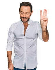 Middle age man wearing casual clothes showing and pointing up with fingers number three while smiling confident and happy.