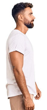 Young hispanic man wearing casual white tshirt looking to side, relax profile pose with natural face with confident smile.