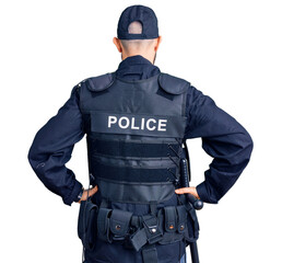Young handsome man wearing police uniform standing backwards looking away with arms on body