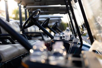 Water bottle in golf carts for golf player on golf course. golf course carts cars at luxury golf club sport venue in neat line row.
