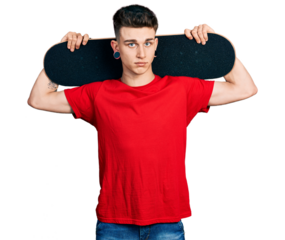Young caucasian boy with ears dilation holding skate over shoulders relaxed with serious expression on face. simple and natural looking at the camera.