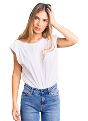 Fototapeta premium Beautiful caucasian woman with blonde hair wearing casual white tshirt confuse and wonder about question. uncertain with doubt, thinking with hand on head. pensive concept.