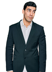 Handsome hispanic man wearing business clothes smiling looking to the side and staring away thinking.