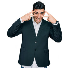 Handsome hispanic man wearing business clothes doing peace symbol with fingers over face, smiling cheerful showing victory