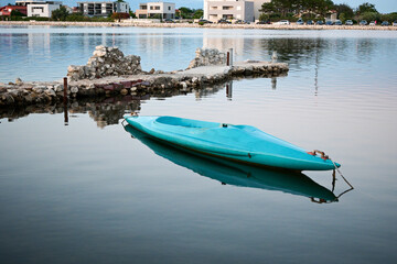 old blue dilapidated kayak at sea