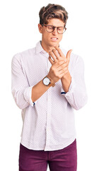 Young handsome man wearing business clothes and glasses suffering pain on hands and fingers, arthritis inflammation