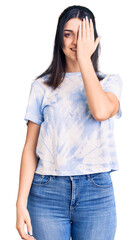 Fototapeta premium Young beautiful girl wearing casual t shirt covering one eye with hand, confident smile on face and surprise emotion.
