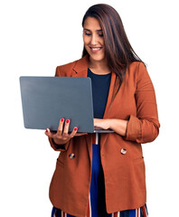 Young beautiful brunette woman using laptop looking positive and happy standing and smiling with a confident smile showing teeth