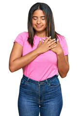 Young latin girl wearing casual clothes smiling with hands on chest with closed eyes and grateful gesture on face. health concept.