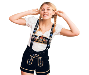 Young beautiful blonde woman wearing oktoberfest dress smiling pulling ears with fingers, funny gesture. audition problem