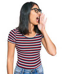 Beautiful asian young woman wearing casual clothes and glasses shouting and screaming loud to side with hand on mouth. communication concept.