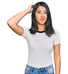 Fototapeta premium Beautiful asian young woman wearing casual white t shirt confuse and wonder about question. uncertain with doubt, thinking with hand on head. pensive concept.