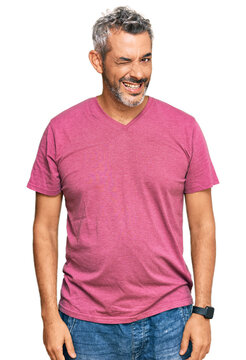 Middle age grey-haired man wearing casual clothes winking looking at the camera with sexy expression, cheerful and happy face.