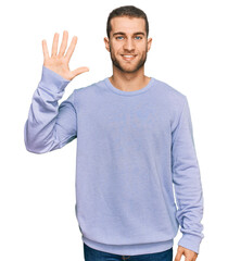Naklejka premium Young caucasian man wearing casual clothes showing and pointing up with fingers number five while smiling confident and happy.