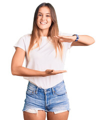 Beautiful caucasian woman wearing casual white tshirt gesturing with hands showing big and large size sign, measure symbol. smiling looking at the camera. measuring concept.