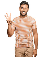 Handsome hispanic man wearing casual clothes showing and pointing up with fingers number three while smiling confident and happy.