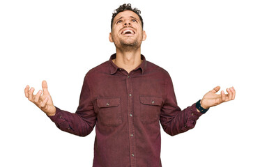 Fototapeta premium Young hispanic man wearing casual clothes crazy and mad shouting and yelling with aggressive expression and arms raised. frustration concept.