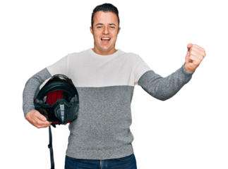 Handsome young man holding motorcycle helmet screaming proud, celebrating victory and success very excited with raised arms